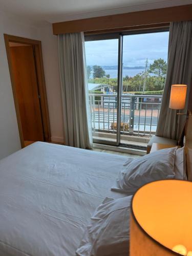 a bedroom with a bed and a large window at Hotel Canelas in Portonovo