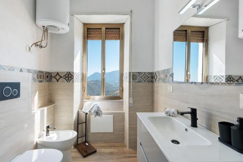 a white bathroom with a sink and a toilet at Ammentos La Casa di Rosa in Orgosolo
