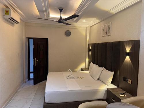 a bedroom with a bed and a ceiling fan at Texas Royal Hotel in Pokuase