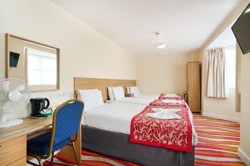 a hotel room with a bed and a desk and a desk at Cranbrook Hotel in Ilford