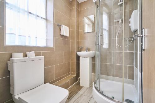 a bathroom with a toilet and a sink and a shower at Cranbrook Hotel in Ilford