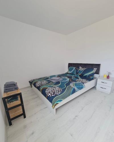 a white bedroom with a bed with a colorful blanket at Ferma DAC in Galaţi