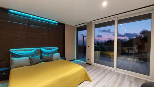 a bedroom with a yellow bed and a large window at Mycelio Atlantic Residence with Atlantic View in Ribamar