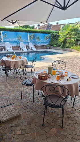 two tables and chairs with food on them next to a pool at Villa Laura B&B in Fossano
