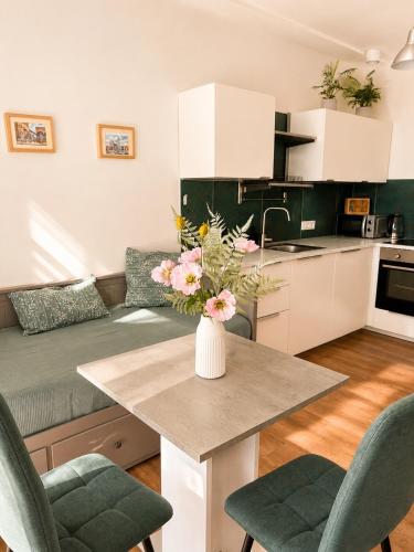 a kitchen and living room with a vase of flowers on a table at TRIO apartment in Piešťany