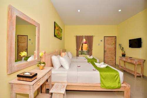 a bedroom with a large white bed and a mirror at The Rani Garden Bed & Breakfast in Denpasar