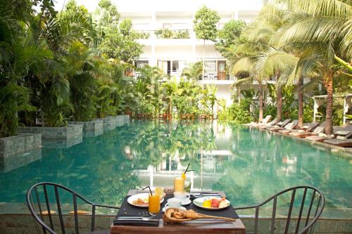 a table with food and drinks next to a swimming pool at Plantation Urban Resort & Spa in Phnom Penh