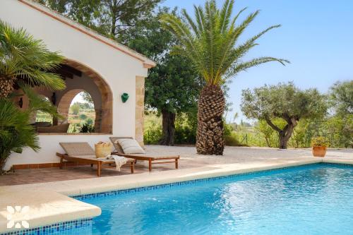 a villa with a swimming pool and a palm tree at Villa Fantaxat by Abahana Villas in Benissa
