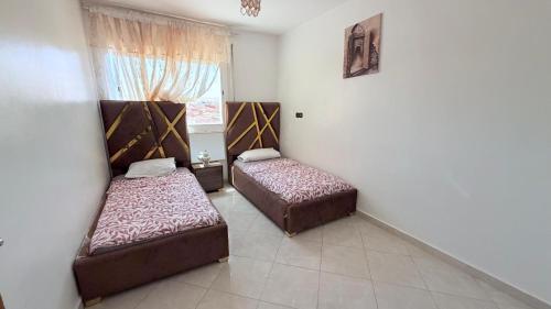 two beds in a room with a window at marhaba apartement in Oujda