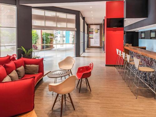 a living room with a red couch and a bar at ibis Blumenau in Blumenau