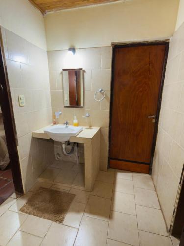 a bathroom with a sink and a wooden door at Atardecer Cabaña frente al rio in Ituzaingó