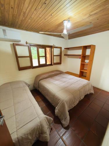 a bedroom with two beds and a wooden ceiling at Atardecer Cabaña frente al rio in Ituzaingó