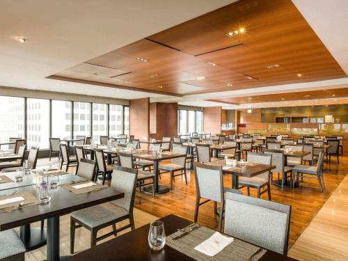 a restaurant with tables and chairs in a room at Ibis Ambassador Myeongdong in Seoul