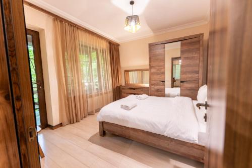 a bedroom with a white bed and a wooden wall at Maestro Rest House Dilijan in Dilijan
