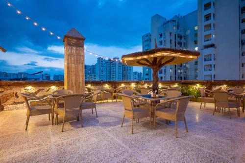 a patio with tables and chairs and an umbrella at Treebo Premium The Maulshri, Behind Health Vistaar City in Lucknow