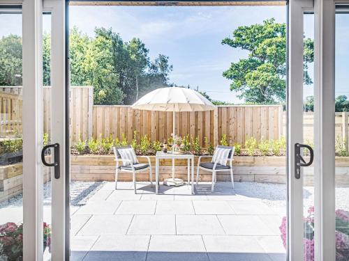 a patio with a table and two chairs and an umbrella at Olchard Lodge in Newton Abbot
