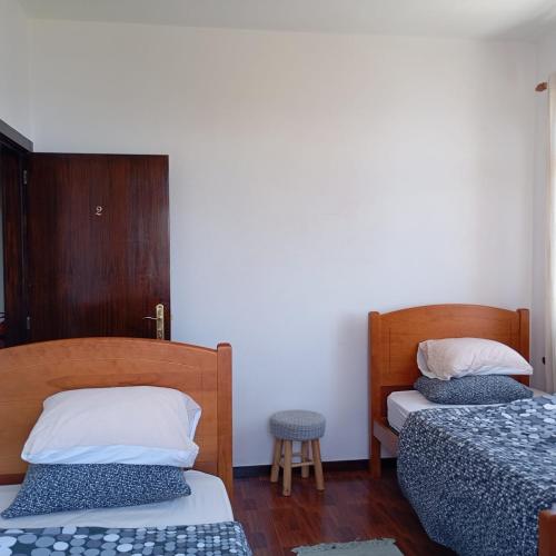 a bedroom with two beds and a table and a stool at Yellow Owl II Bedroom II in Campanário