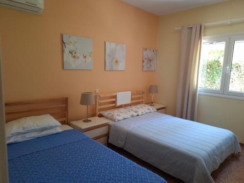 a bedroom with two beds and a window at Lagonissi Summer House in Lagonissi