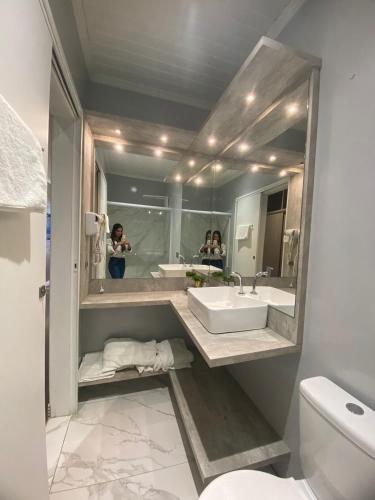 two people taking pictures in a bathroom mirror at Hotel Morro dos Conventos in Araranguá