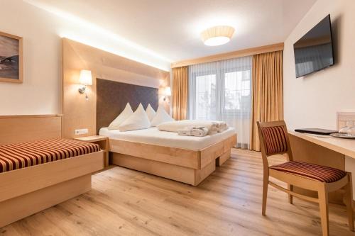 a hotel room with a bed and a desk at Hotel Albona in Ischgl