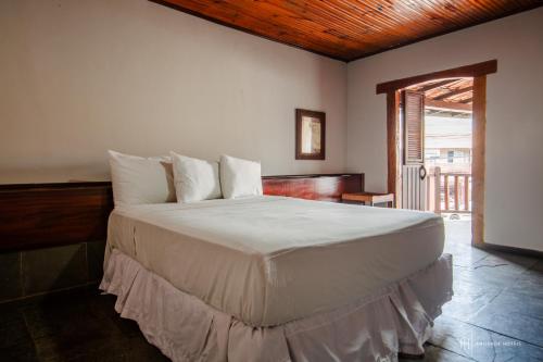 a bedroom with a large bed with white sheets at Rede Andrade Galeão in Porto Seguro