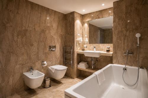 a bathroom with a tub and a toilet and a sink at Astoria Grand Hotel in Sofia