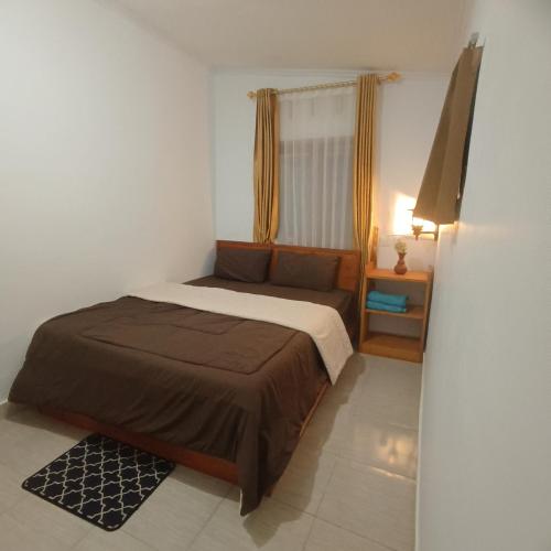 a small bedroom with a bed and a window at Tetebatu Clove Garden in Tetebatu