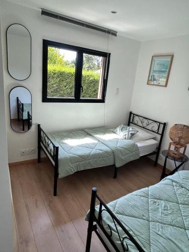 a bedroom with two beds and a window at Le Chalet de Kervignon in Plobannalec-Lesconil