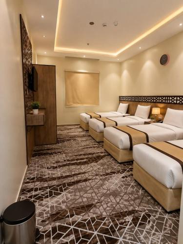 a hotel room with four beds and a projection screen at فندق جوهرة الحجاز توصيل من والى الحرم مجاناً in As Sifyānī