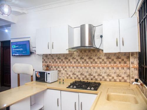 a kitchen with white cabinets and a stove top oven at Queen Tori in Malindi