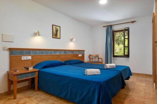 a bedroom with two blue beds and a desk at Santuari de Lluc in Lluc