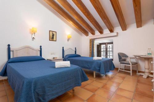 a bedroom with two beds and a table and chairs at Santuari de Lluc in Lluc