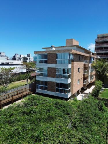 an apartment building with a lawn in front of it at Refúgio dos Guaiás - Apart Hotel in Bombinhas