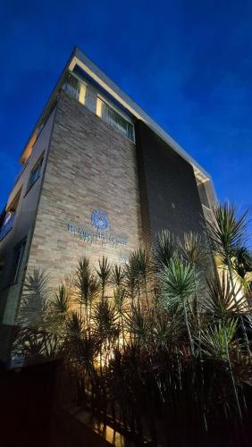 a building with palm trees in front of it at Refúgio dos Guaiás - Apart Hotel in Bombinhas