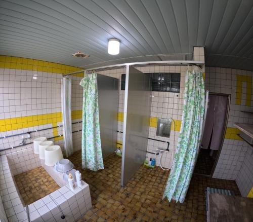 a bathroom with a shower and toilets in it at Adventure Hostel う島や in Iriomote