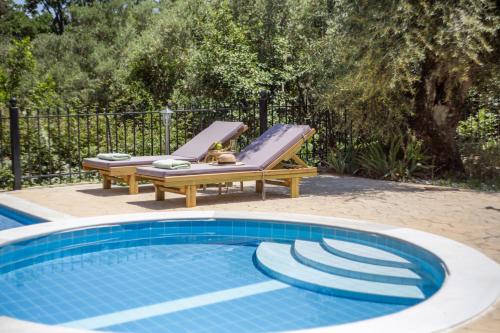 a pool with a lounger and a lounge chair next to a swimming pool at Apanema Mindfulness, Relaxing Adults Only Resort, Fast WiFi, Pool, Sauna, Massage in Asprogerakata