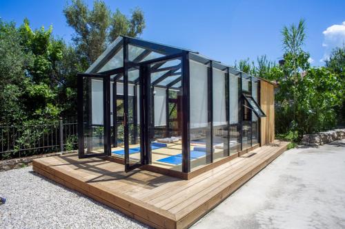 a glass house sitting on a wooden deck at Apanema Mindfulness, Relaxing Adults Only Resort, Fast WiFi, Pool, Sauna, Massage in Asprogerakata