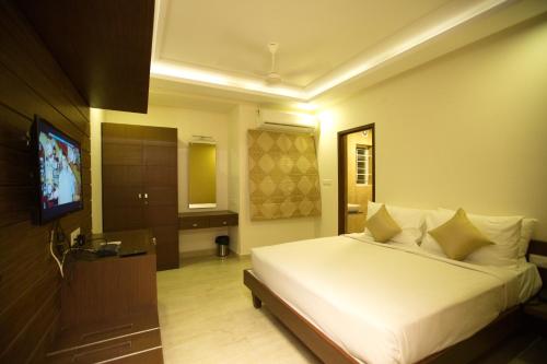 Schlafzimmer mit einem weißen Bett und einem TV in der Unterkunft The Summit Luxury Apartments - Monthly Accommodation in Chennai
