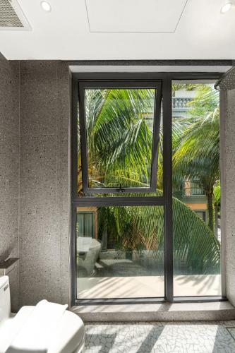 a bathroom with a toilet and a large window at Maison Thu in Phú Quốc