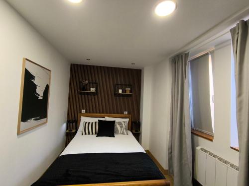 a bedroom with a black and white bed and a window at Casa Stone in Guarda