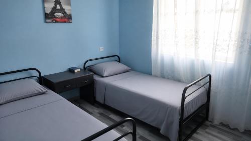 two beds in a room with blue walls and a window at Rokiti Yard in Bagdatʼi