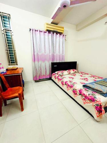 a bedroom with a bed and a chair and a desk at Ast Guest House in Dhaka