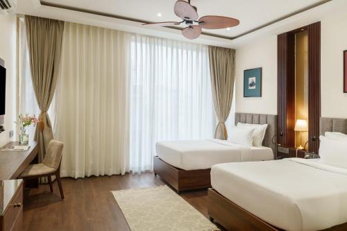 a hotel room with two beds and a ceiling fan at Oraka by My Downtown Aura Hotel in Udaipur