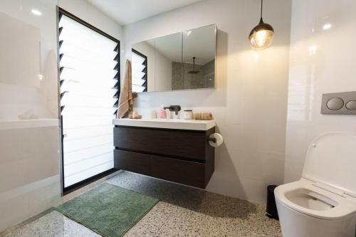 a bathroom with a toilet and a sink and a mirror at The Graceful Dodeca Treehouse Coalcliff 