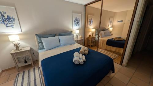 a bedroom with a bed with blue sheets and a mirror at Maison bord de mer - piscine - in Théoule-sur-Mer