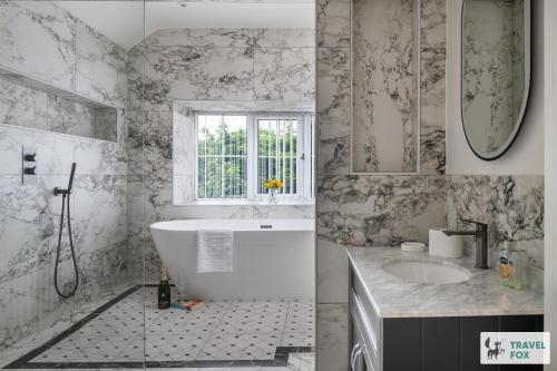 a bathroom with a tub and a sink and a mirror at The Plas - Rhosneigr Manor House in Rhosneigr