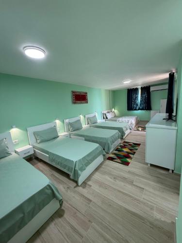 a room with four beds and a flat screen tv at Bujtina e Qilimave in Zogaji