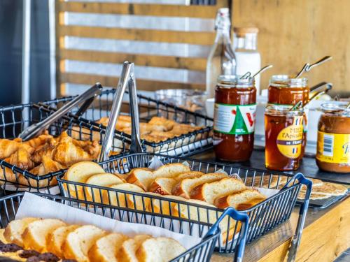 a table topped with baskets of bread and jars of honey at ibis budget La Roche Sur Yon Vendespace in Mouilleron-le-Captif