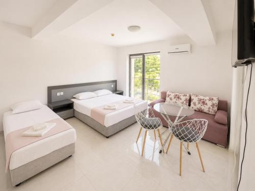 a bedroom with two beds and a couch and a table at Хотел Дани in Sandanski