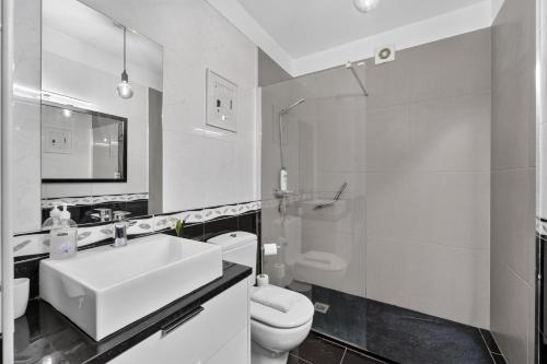 a white bathroom with a sink and a toilet at Casa da Abegoaria in Caniço